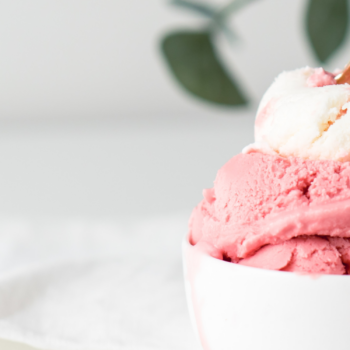 A photograph of a bowl of raspberry sorbet with a golden spoon.